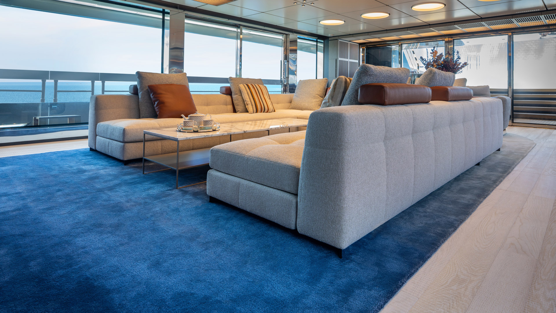 Navy blue rug in a sea-view lounge with gray sectional sofa and marble coffee table