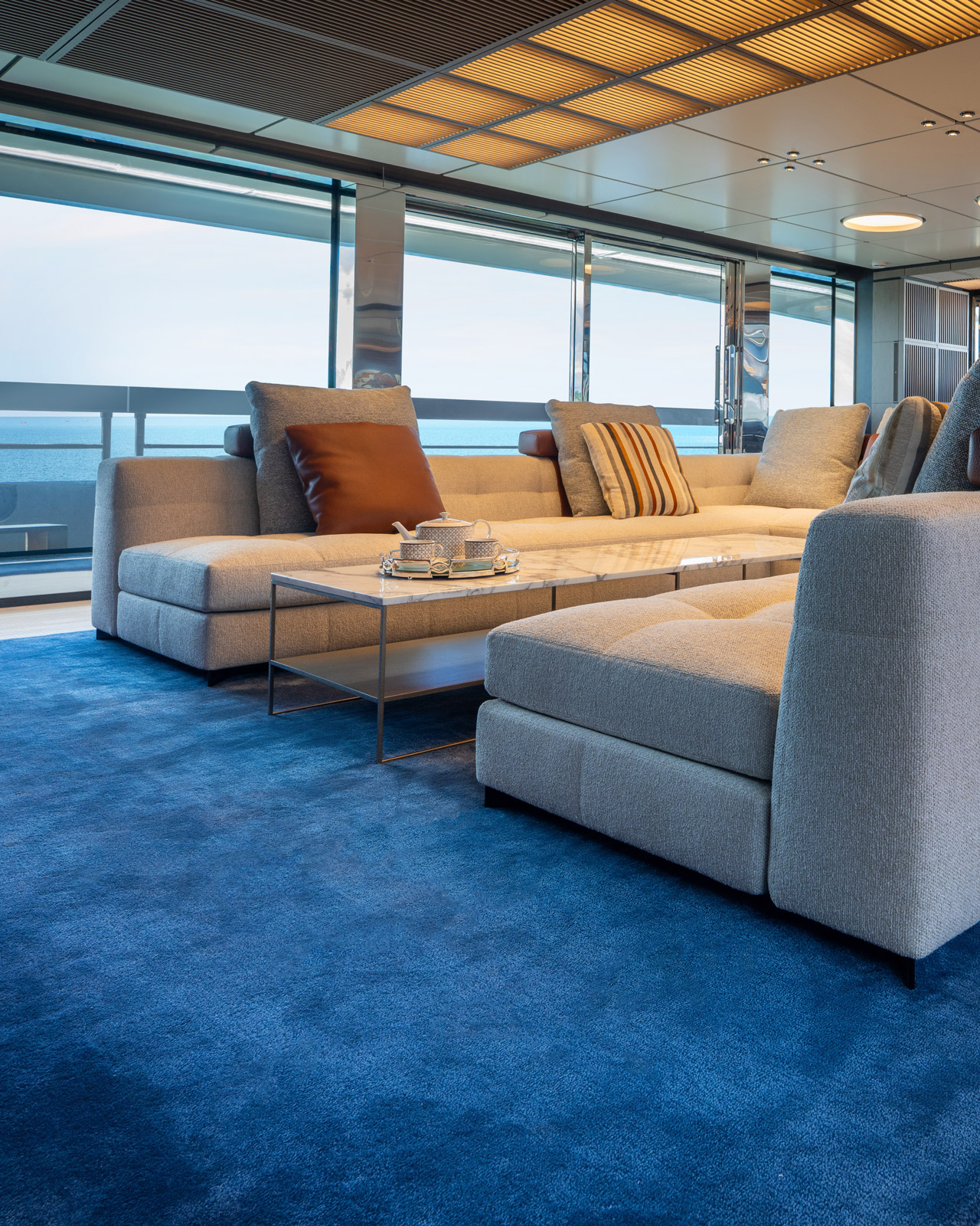 Navy blue rug in a sea-view lounge with gray sectional sofa and marble coffee table