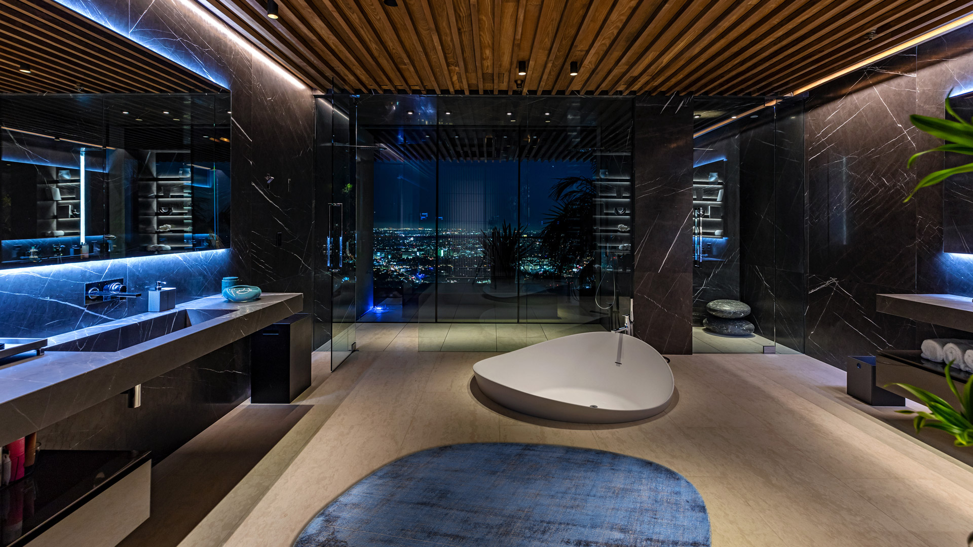Round light-blue rug in a design bathroom with dark marble and freestanding tub