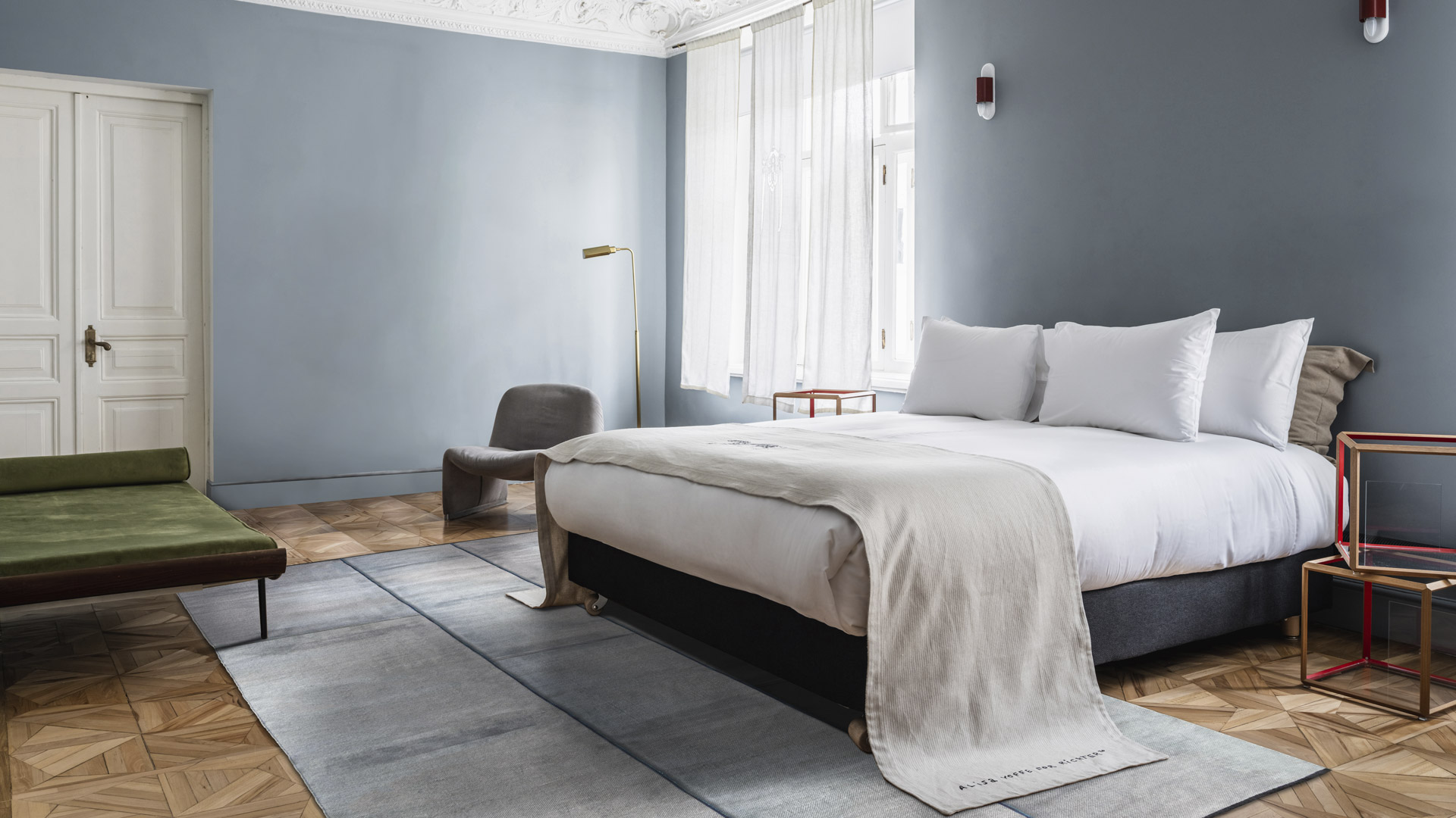 Gray-blue rug in a bedroom with blue-gray walls and herringbone wood flooring