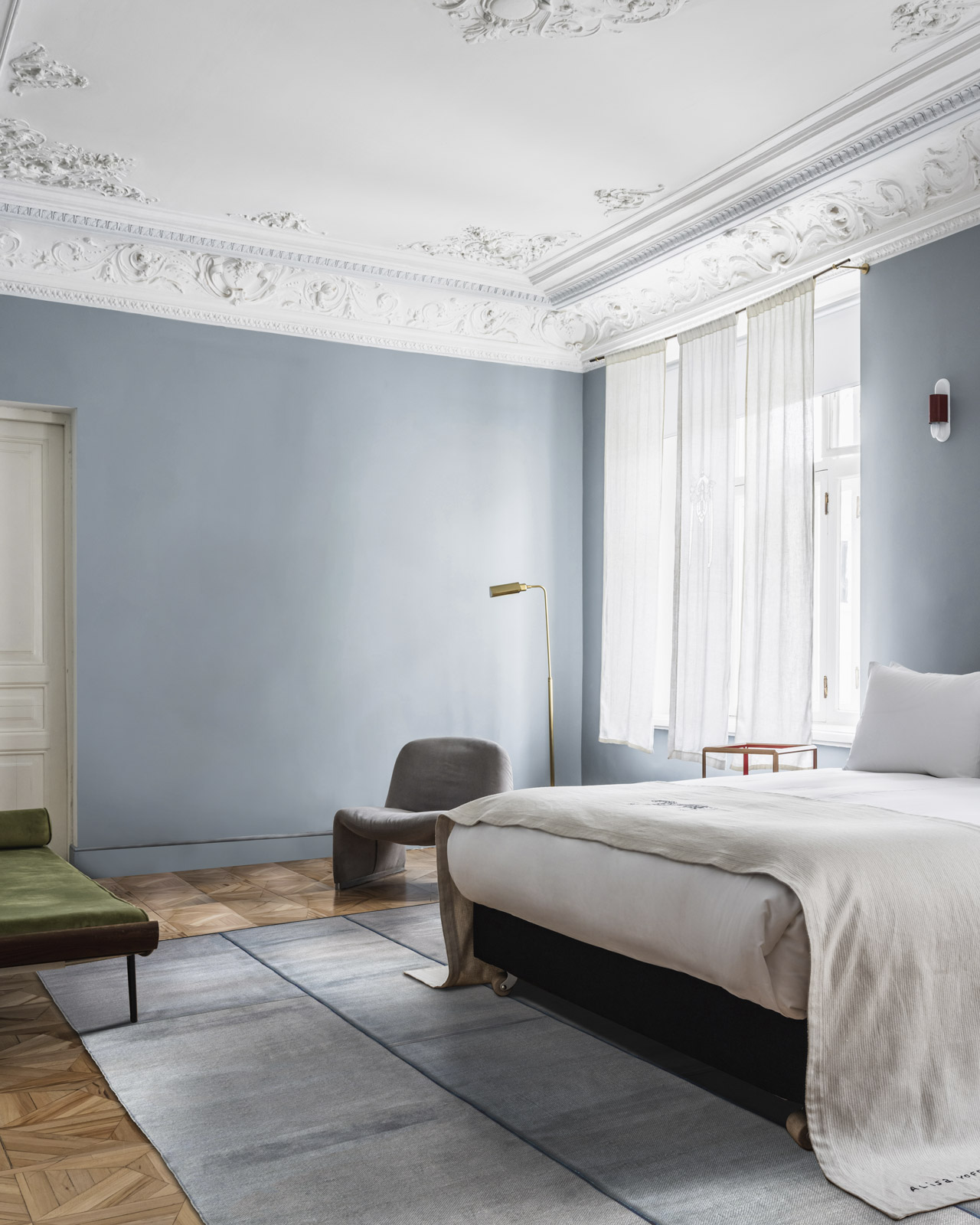 Gray-blue rug in a bedroom with blue-gray walls and herringbone wood flooring