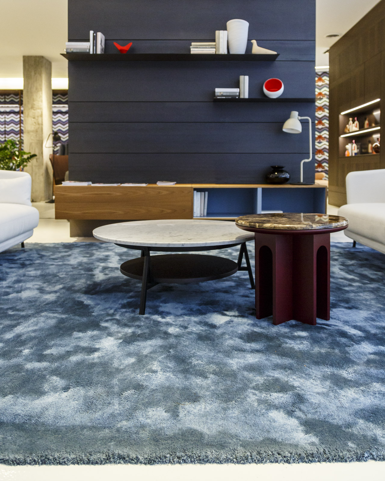 Blue rug that defines an open living area with hardwood floors and furnishings in warm, neutral tones